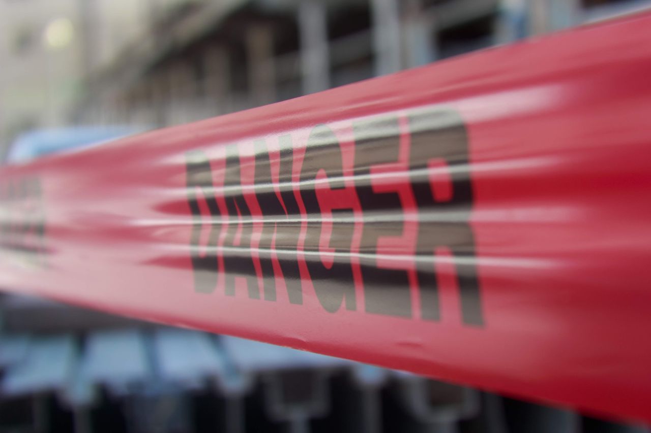 Focused close-up of red danger barricade tape at a construction site.